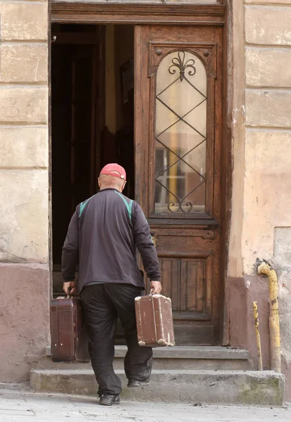 Hombre con maleta entra por la vieja puerta, atrás —  Fotos de Stock