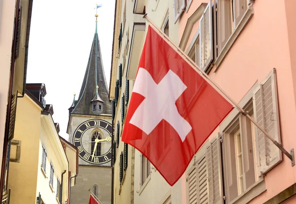 Menara jam Gereja Santo Petrus dan Bendera Swiss di gedung fasad di Zurich, Swiss — Stok Foto