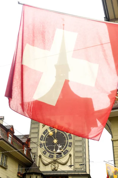 Schweizer Flagge vor dem berühmten Uhrenturm in bern, Schweiz. — Stockfoto