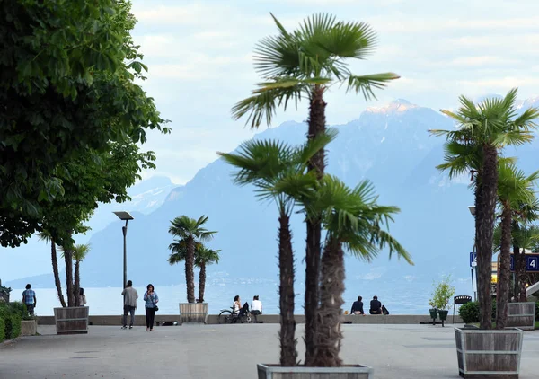 Personas en el terraplén en el lago de Ginebra por la noche, Lausana, Suiza . — Foto de Stock