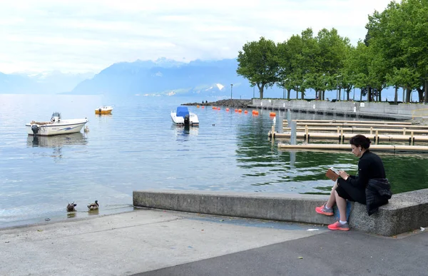 Žena číst knihu na břehu Ženevského jezera v Lausanne. — Stock fotografie