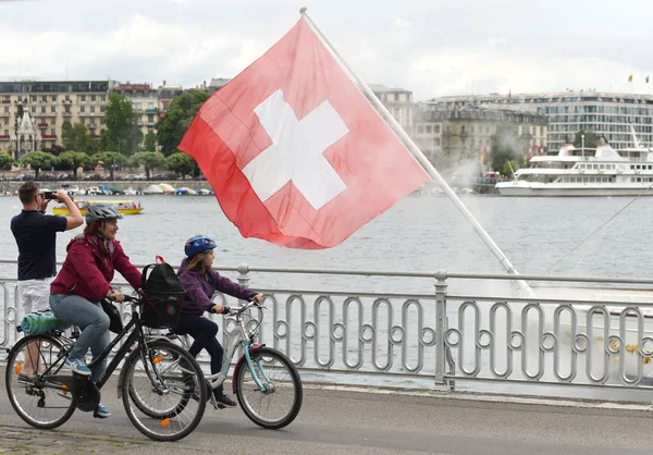 Schweiziska flaggan och personer på banvallen i Genève, Schweiz. — Stockfoto