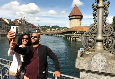 Couple makes selfie at the embankment lake Lucerne with Chapel Bridge (Kapellbrucke) and Water Tower at the background, Switzerland. clipart