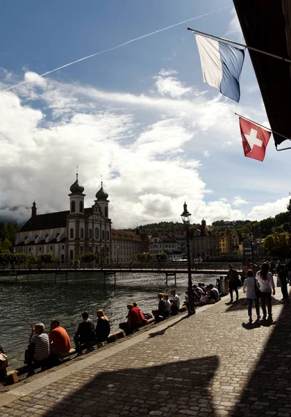 Az emberek a töltésen Luzerni-tóra és a jezsuita templom a háttérben, Svájc Luzern utca-és városrészlet. — Stock Fotó