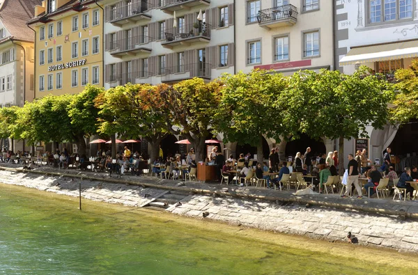 Emberek pihenhetnek a kávézóban a a partra átfolyó Reuss folyón található Luzern, Svájc. — Stock Fotó