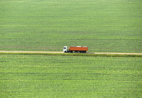 El camión va en la carretera en un campo verde, vista superior — Foto de Stock