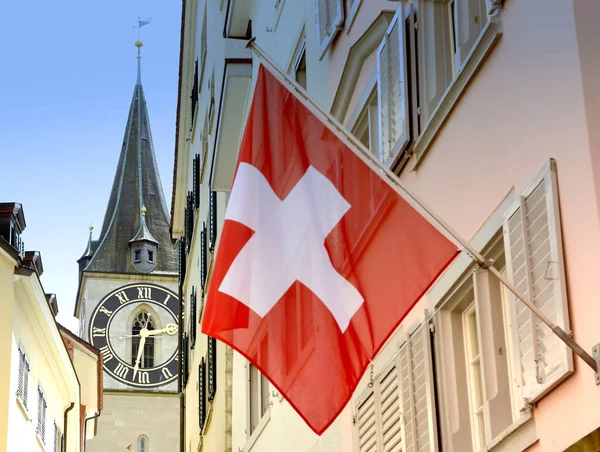 Uhrturm der Peterskirche und Schweizer Flagge am Fassadengebäude in Zürich, Schweiz — Stockfoto