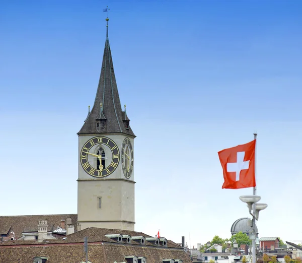 Uhr Turm der Peterskirche und Schweizer Flagge an der Fassade — Stockfoto