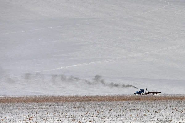 Τρακτέρ κατά την εργασία σε ένα χιονισμένο πεδίο νωρίς την άνοιξη. καλλιεργήσιμο έδαφος — Φωτογραφία Αρχείου