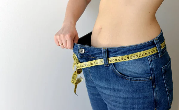 Koncept ztráta hmotnosti. Žena ukazuje její úbytek na váze tím, že nosí o — Stock fotografie