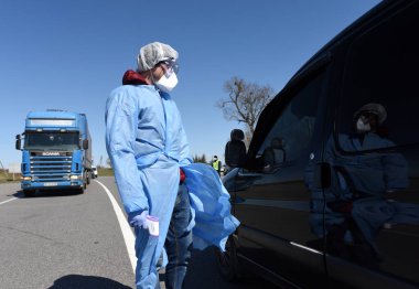 Lviv, Ukrayna - 10 Nisan 2020: Tıp çalışanı Lviv bölgesinin girişindeki bir kontrol noktasında bir sürücünün sıcaklığını kontrol ediyor. Koronavirüs COVID-19 salgını nedeniyle Ukrayna 'daki karantina kısıtlamaları.