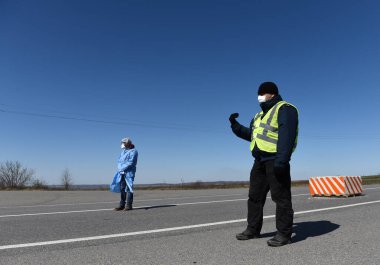 Lviv, Ukrayna - 10 Nisan 2020: Tıp çalışanı Lviv bölgesinin girişindeki bir kontrol noktasında bir sürücünün sıcaklığını kontrol ediyor. Koronavirüs COVID-19 salgını nedeniyle Ukrayna 'daki karantina kısıtlamaları.
