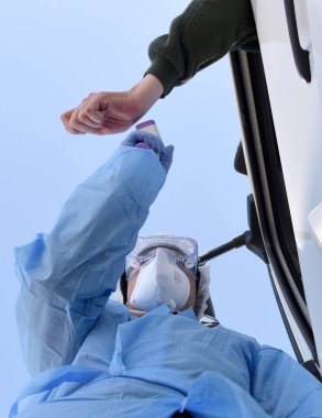 Lviv, Ukrayna - 10 Nisan 2020: Tıp çalışanı Lviv bölgesinin girişindeki bir kontrol noktasında bir sürücünün sıcaklığını kontrol ediyor. Koronavirüs COVID-19 salgını nedeniyle Ukrayna 'daki karantina kısıtlamaları.