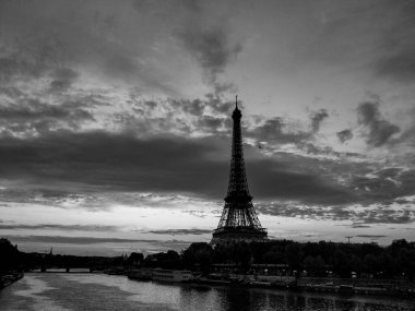 Paris, Fransa 'da, bulutlu bir gökyüzü arkaplanıyla gün doğumunda Eyfel Kulesi ve Seine Nehri' nin Siyah ve Beyaz Görünümü