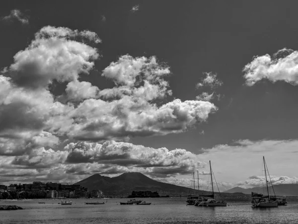 Black and White Photography of Vesuvius seen from the Naples bay with fishing boats in the foreground.