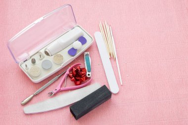 Manikür ve pedikür araçlar üzerinde pembe bir arka plan, üstten görünüm.