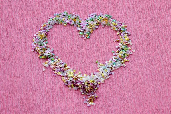 Heart shape of sequins, shimmer and confetti for manicure design on bright pink background.