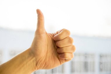 Erkek el başparmak yukarıya işareti doğal ışık arka plan karşı gösterilen closeup