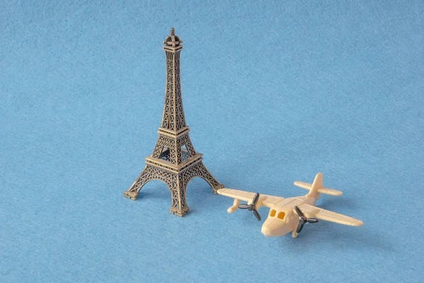 Eifelturmmodell mit kleinem Spielzeugflugzeug auf blauem Hintergrund. berühmtes französisches Wahrzeichen und Flugzeugminiaturen, Konzept für Paris-Souvenirs. — Stockfoto