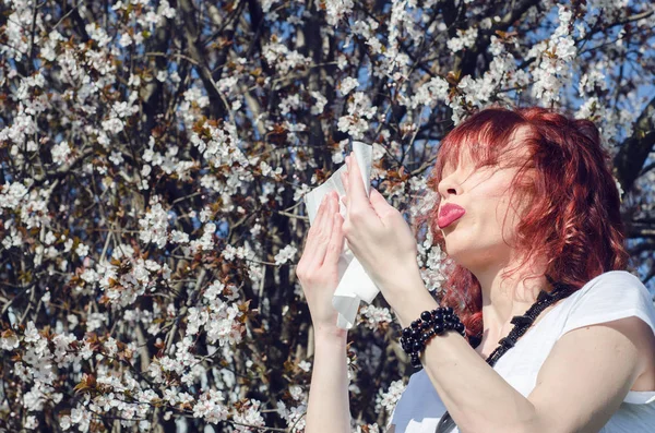 Beautiful woman sneezing into a tissue — Stock Photo, Image