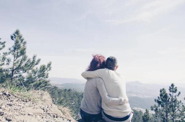 Niño y niña se sientan abrazados en la montaña — Foto de Stock