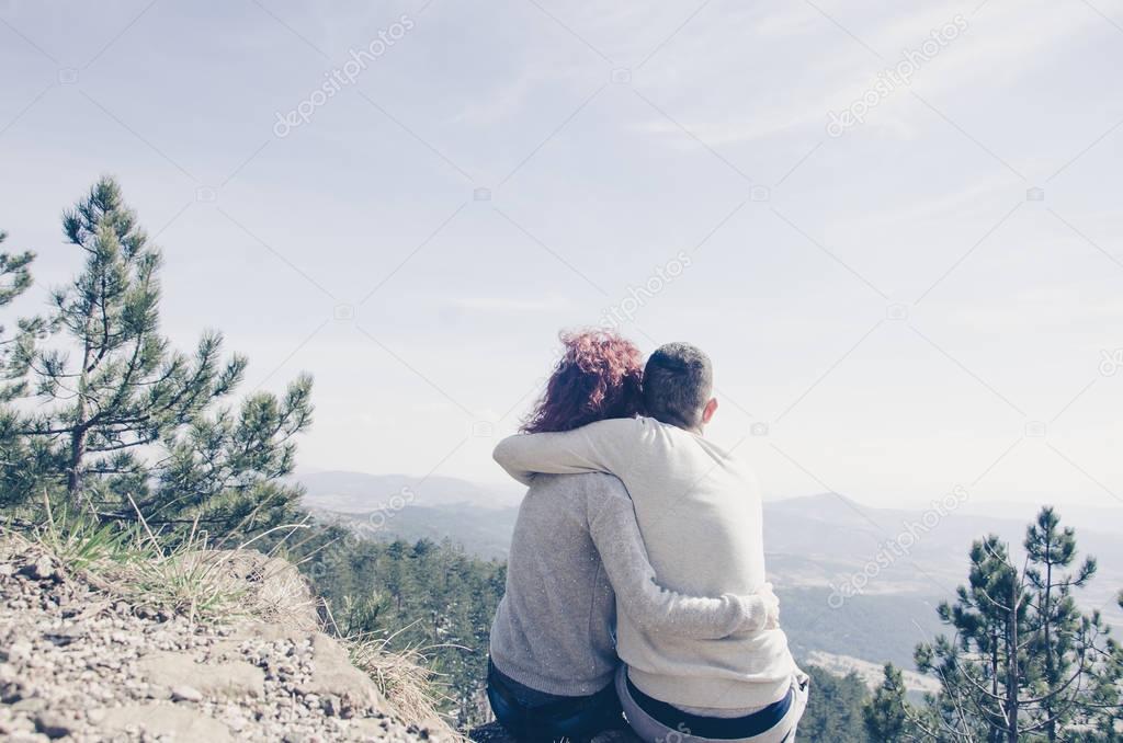 boy and girl sit cuddled on the mountain 