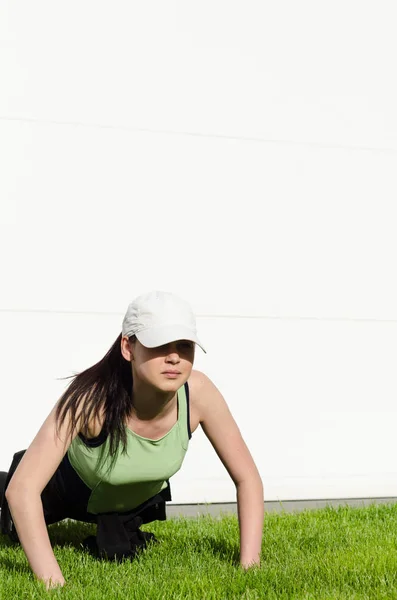 Chica joven con una gorra haciendo flexiones — Foto de Stock