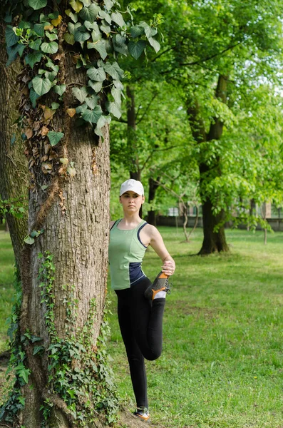 Девушка в кепке упражнения в парке — стоковое фото