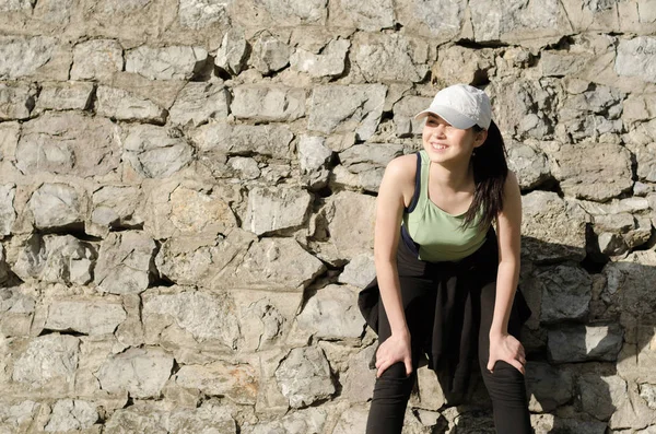 Mädchen müde nach einem Training vor einer Steinmauer stehend und — Stockfoto