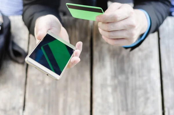 Tarjeta de crédito y teléfono móvil en mano — Foto de Stock