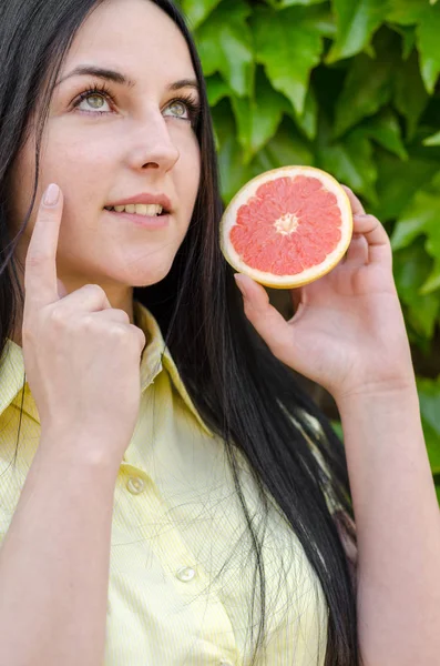 美しい若い女性の顔にフルーツ ジュースを適用し 自然な方法で皮膚に栄養を与える — ストック写真