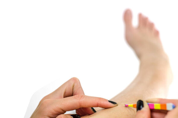 Девушка дергает волосы с ног пинцетом
