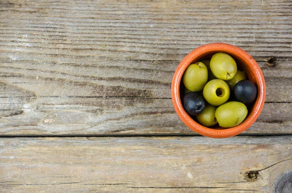 Green and black olives in a clay pot