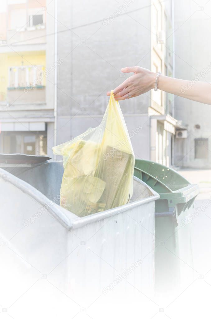 hand throwing plastic bag with trash