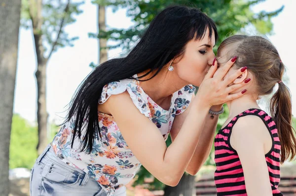 Mamma kyssa sitt barn i naturen eller park — Stockfoto