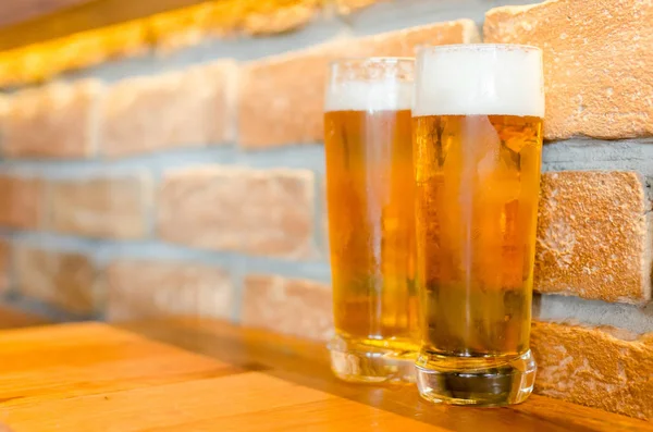 Two glasses of beer on a retro brick wall