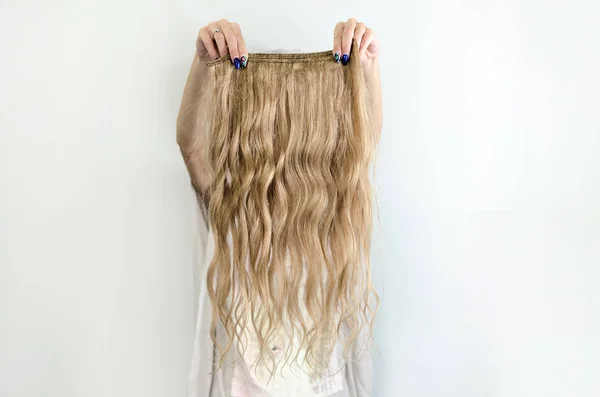 Mão feminina segurando cabelo loiro ondulado — Fotografia de Stock