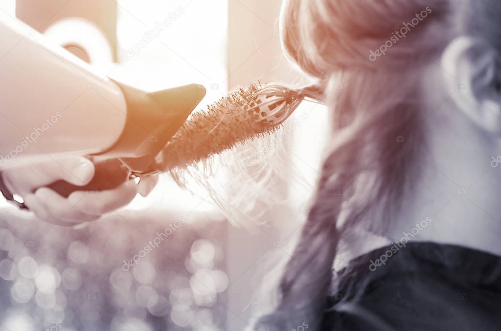 Hairdresser hands holding hair dryer and drying client hair in beauty salon