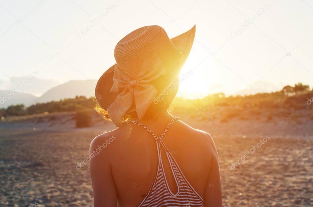 back of woman walking toward the sunset