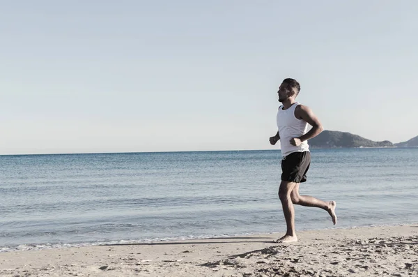 Человек бежит по тропическому пляжу — стоковое фото