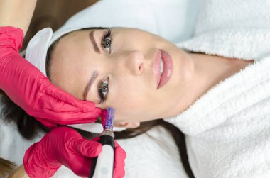 Beautician performs a micro needle mesotherapy treatment on face. clipart