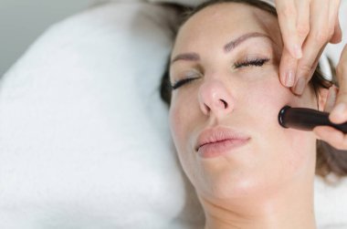 Erkek yüz tedavisinde radyo dalgaları yüz dermatolog ofiste kaldırma ile zevk Kapalı gözlerle closeup.