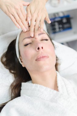 Masör kadın yüzü masajlar ve alın kırışıklıkları kaldırır ve spa Güzellik Salonu içinde cildi sıkılaştırır.