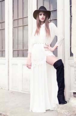 Beyaz uzun elbise ve siyah çizmeler eski retro kapılar önünde poz şehvetli ciddi kadın.