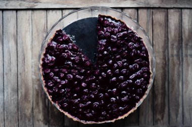 Vanilyalı ve ahşap masada siyah kirazlı ev yapımı vişneli pasta.