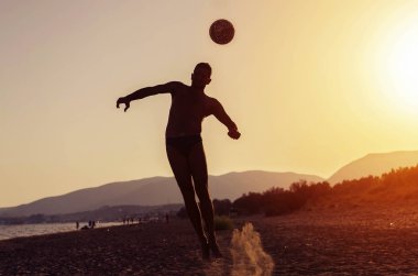 Spor adam top baş ve deniz kenarında günbatımı plaj üzerinde atlama ile çekim veya hiting. Metin için yer