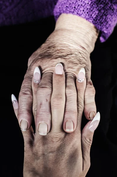 Support hands with crossed fingers of old and young women.