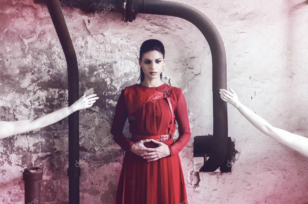 Portrait of beautiful depressed woman in red dress with imaginary hands for help.