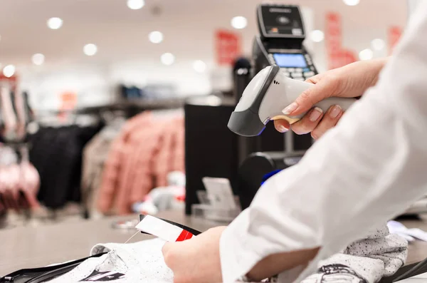 Cropped shot of female hand, Woman or worker holding bar code scanner and scanning card or paper on clothes