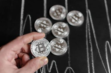 Bitcoin çoğaltma Siyah Kara tahta arka plan üzerinde tutan işadamı el Close-Up